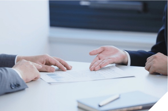 Two people exchanging a signed document across a desk